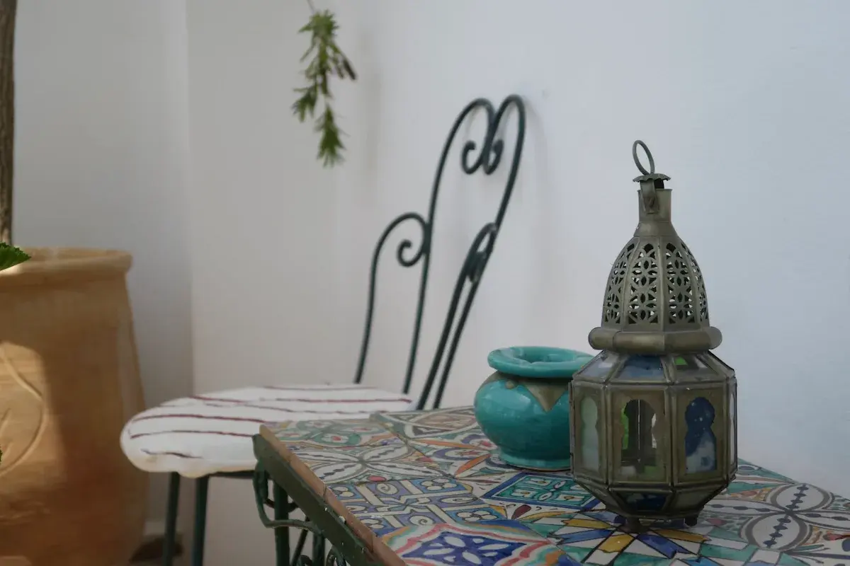 Balcony seating area in the Junior Suite of Kasbah Rose guesthouse, featuring traditional Moroccan table and chair with ornate metalwork, offering a perfect spot to enjoy morning coffee while overlooking the medina