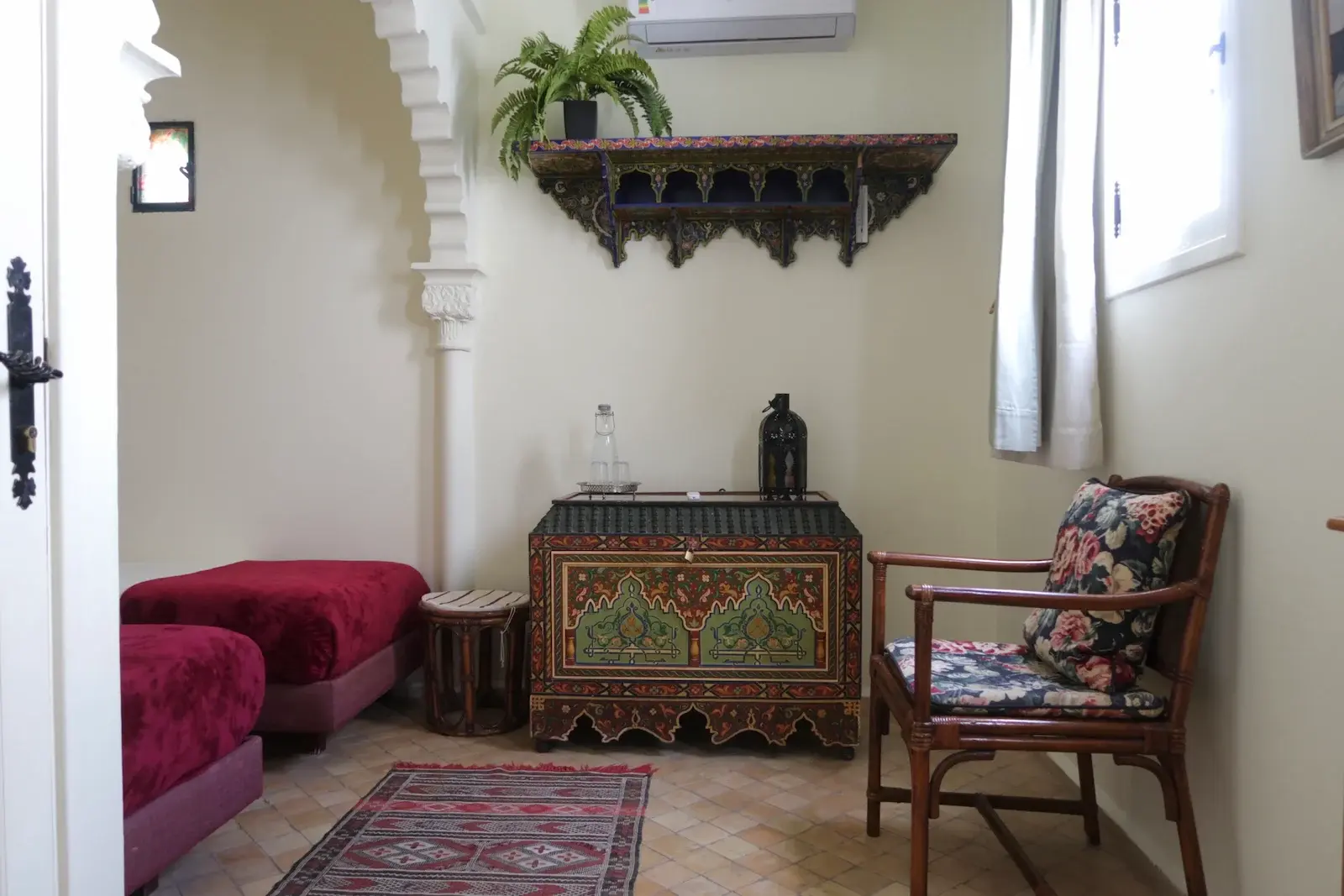 Le coffre marocain traditionnel et la chaise en bambou avec un coussin à fleurs dans la chambre Double ou Twin.