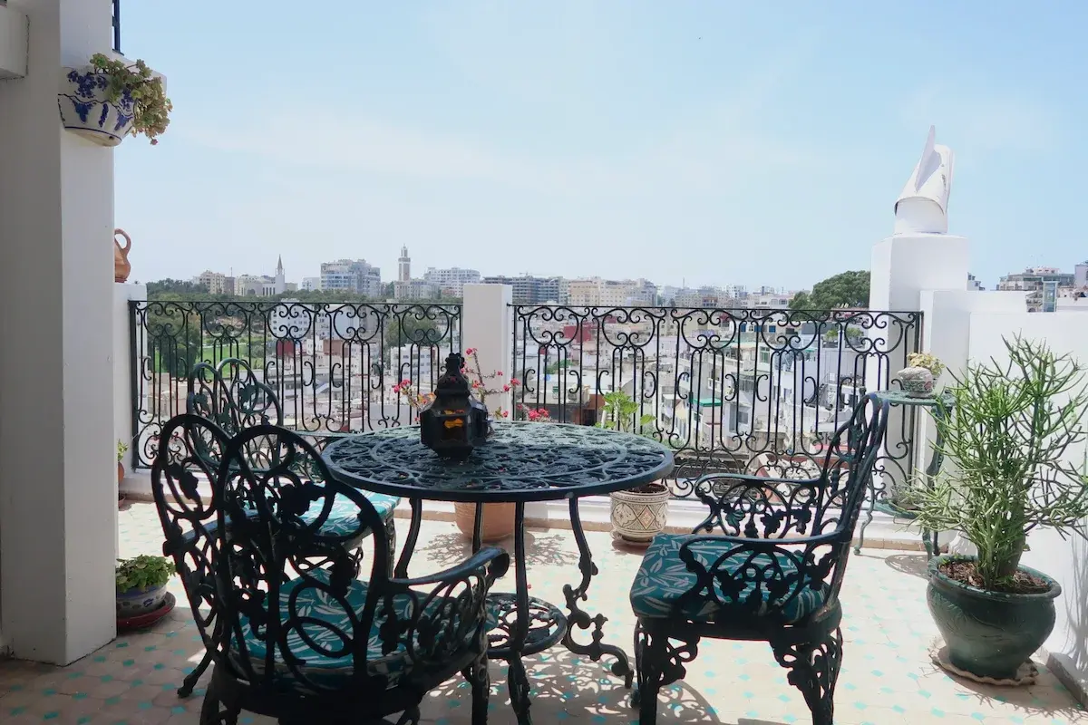 The spacious private terrace of the Senior Suite with metal furniture and a panoramic city view.